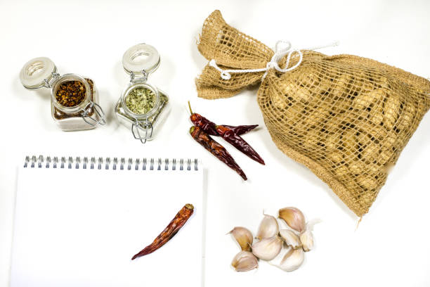 Notes to save the recipes on a white kitchen table. Seasonings, culinary ingredients - peppers, garlic and oil on the table. White background.
