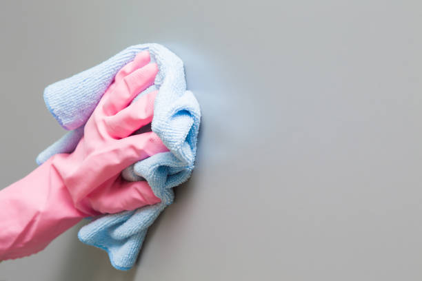 istock Employee hand in rubber protective glove with micro fiber cloth wiping a cupboard surface. Early spring or regular cleanup. Commercial cleaning company concept. 880288188