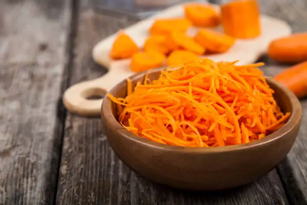 Grate  carrots in a bowl on a wooden table. Tasty and healthy food. Diet.