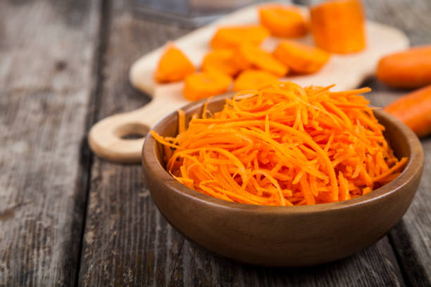 морковь натереть на терке в миске - carotene стоковые фото и изображения
