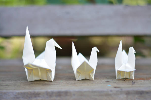 istock Three origami white birds on wooden bench. 880297652