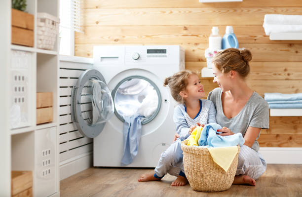 ama de casa feliz madre de familia y el niño en la lavandería con lavadora - stereotypical housewife little girls family domestic kitchen fotografías e imágenes de stock