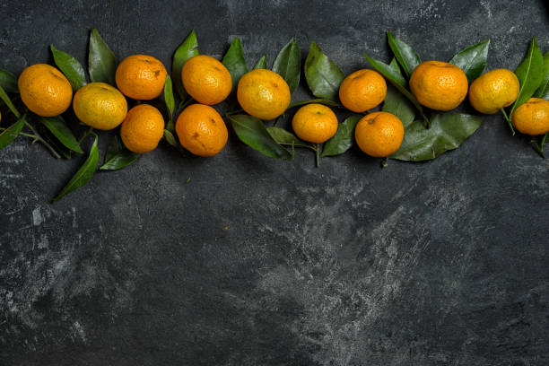 istock mandarines with leaves in a row on a black cement background with copy space for your text 880316922