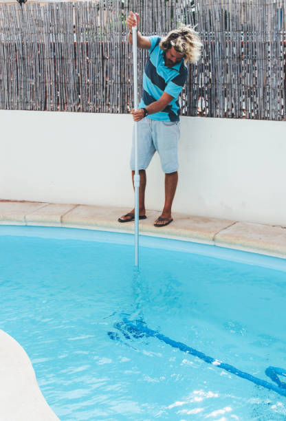 istock Male pool cleaner cleaning a blue pool 880320102