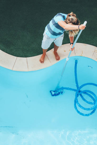 istock Male pool cleaner cleaning a blue pool 880320270