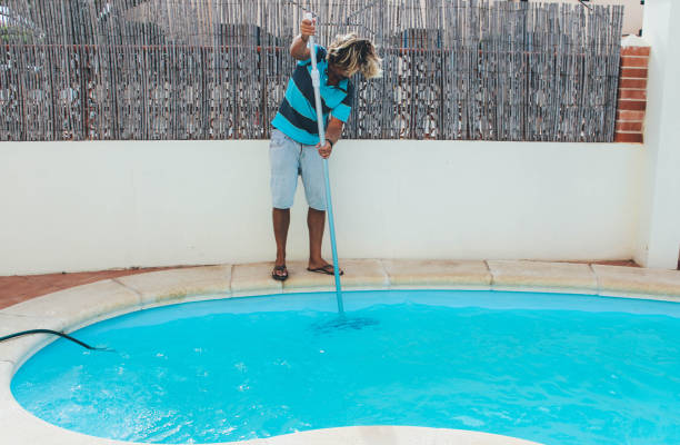 istock Male pool cleaner cleaning a blue pool 880320976