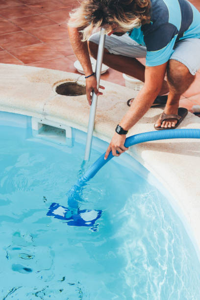 istock Male pool cleaner cleaning a blue pool 880323304