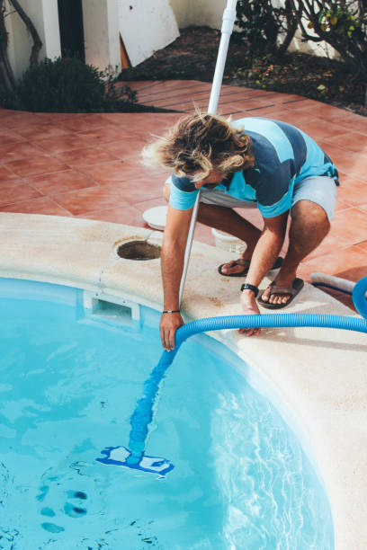 istock Male pool cleaner cleaning a blue pool 880326016
