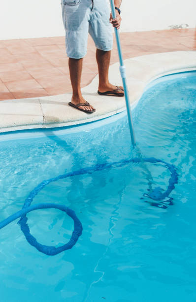 istock Male pool cleaner cleaning a blue pool 880328214