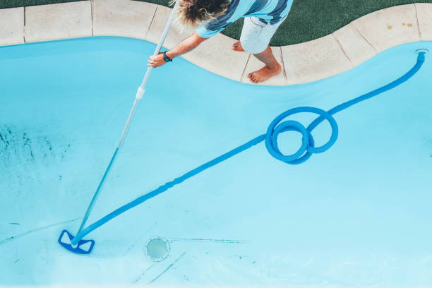 istock Male pool cleaner cleaning a blue pool 880328556