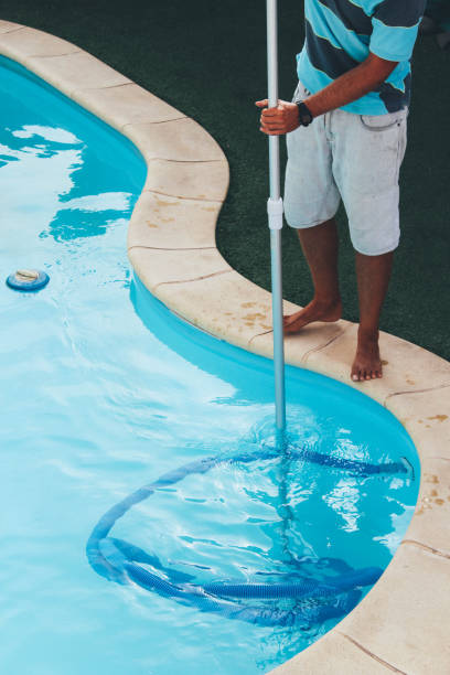 istock Male pool cleaner cleaning a blue pool 880328846