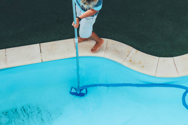 istock Male pool cleaner cleaning a blue pool 880331140