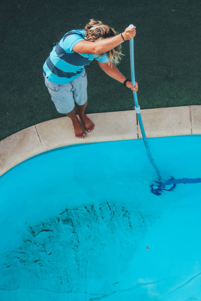 istock Male pool cleaner cleaning a blue pool 880331306