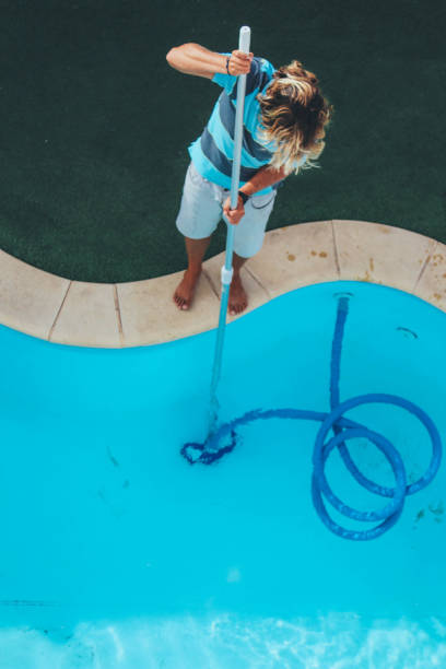 istock Male pool cleaner cleaning a blue pool 880331388