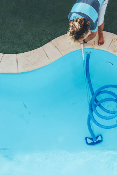 istock Male pool cleaner cleaning a blue pool 880331642