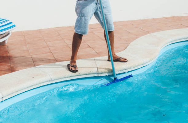 istock Male pool cleaner cleaning a blue pool 880333962