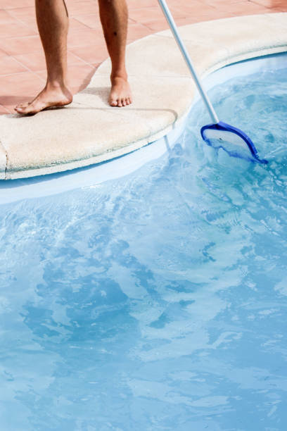 istock Male pool cleaner cleaning a blue pool 880334084