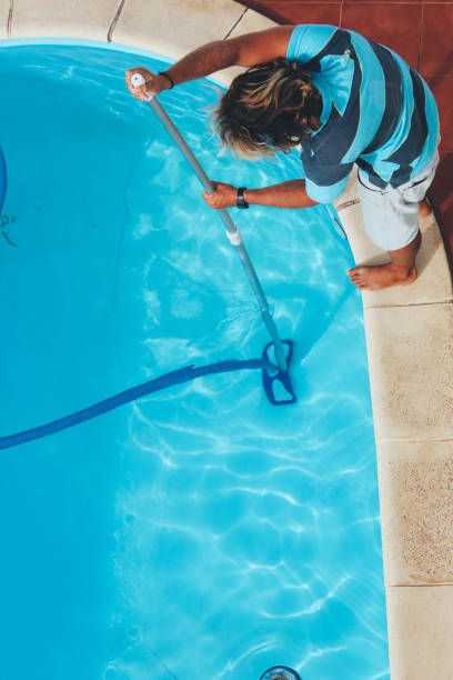 istock Male pool cleaner cleaning a blue pool 880334490