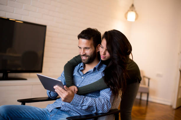 istock Young couple sitting in the living room and using tablet 880334668