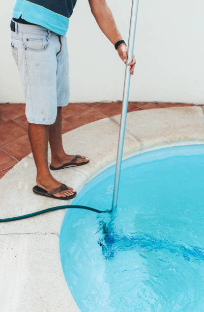 istock Male pool cleaner cleaning a blue pool 880337786