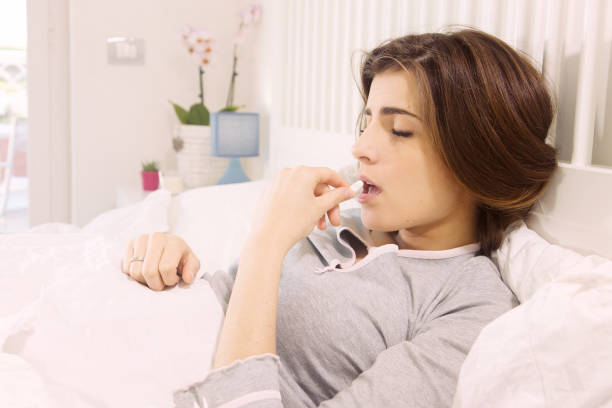 istock Sick woman holding medicine lying in bed 880338550