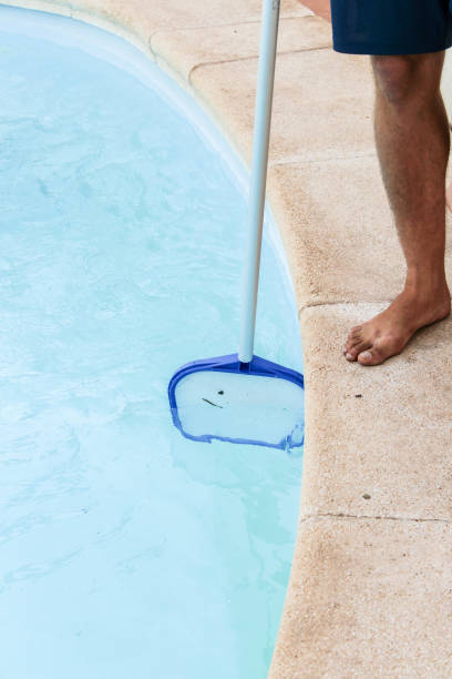 istock Male pool cleaner cleaning a blue pool 880338760
