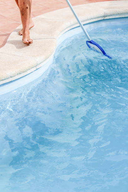 istock Male pool cleaner cleaning a blue pool 880339686