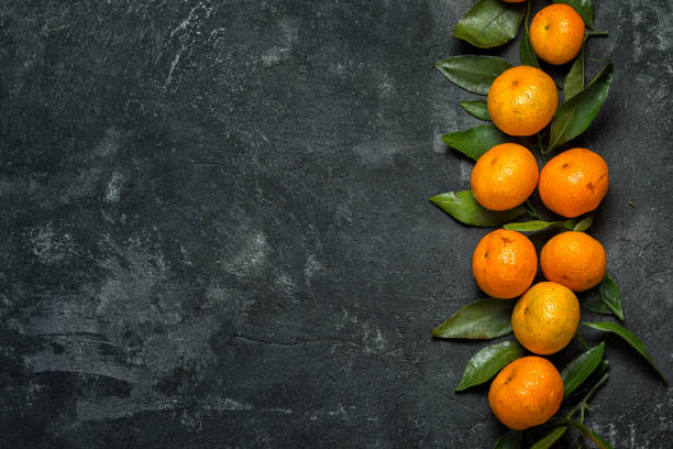 istock Fresh clementines on the black cement background with leaves. Top view with copy space. 880344264