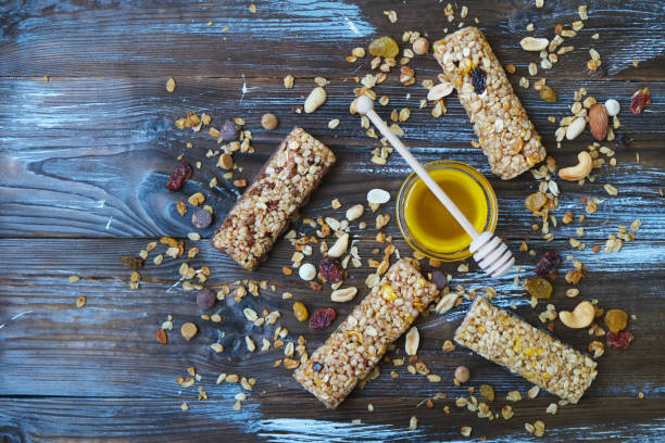 hoher proteingehalt energie müsliriegel auf dunklen braunen holztisch, trockenfrüchte, gemischten nüssen und honig, gesunde superfood. draufsicht, nahaufnahme - wheat whole wheat close up corn on the cob stock-fotos und bilder