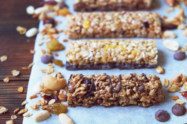 istock Four various nutritious high protein granola power bars laid on the wooden table, mixed nuts, dry fruits and chocolate, healthy superfood. Side view 880344710
