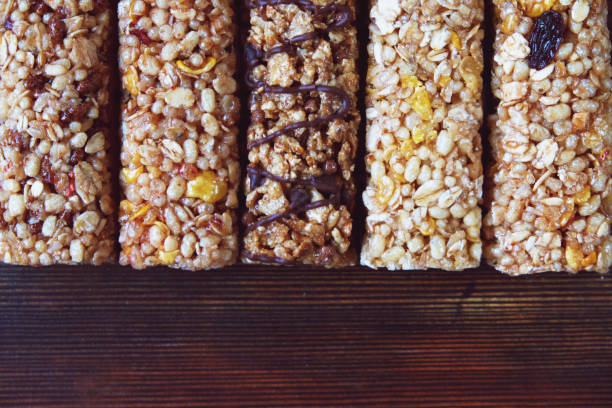 istock Five various nutritious high protein granola power bars laid on the dark brown wooden table, dry fruits and chocolate, healthy super food. Top View, close-up, copy space 880344754