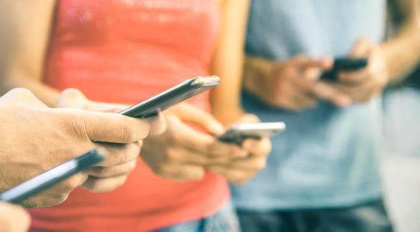 amigos multiculturales a través de smartphone al aire libre - manos de las personas adictas por profundidad teléfono inteligente móvil - concepto de tecnología con conectados hombres y mujeres - de campo en brillante tono filtrado vintage - adicto grupo de jóvenes amigos usando teléfonos móviles fotografías e imágenes de stock