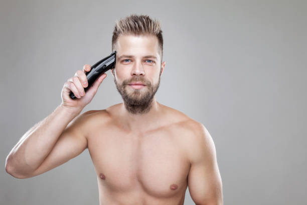 istock Handsome man cutting his own hair with a clipper 880350474
