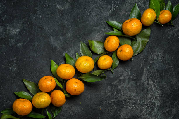 istock mandarines lying in a line on a diagonal on black cement divide the background into two equal parts, top view with copy space 880356224