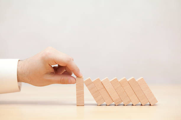 istock Man's hand stopping the domino effect 880362768