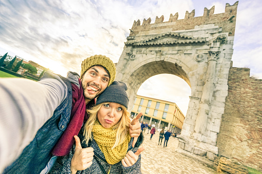 Happy hipster couple taking selfie at european city trip on winter clothes - Fun concept with alternative fashion world travelers - Handsome boyfriend with caucasian girlfriend - Warm afternoon filter
