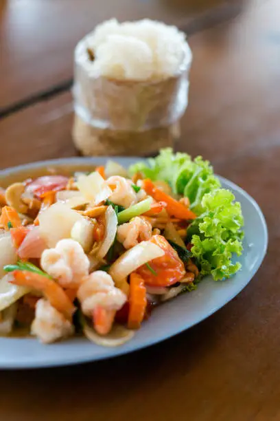 Fresh fried prawns with carrot, onion, tomatoes and cashew nuts served with sticky rice. Traditional thai cuisine.