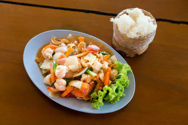 Fresh fried prawns with carrot, onion, tomatoes and cashew nuts served with sticky rice. Traditional thai cuisine.