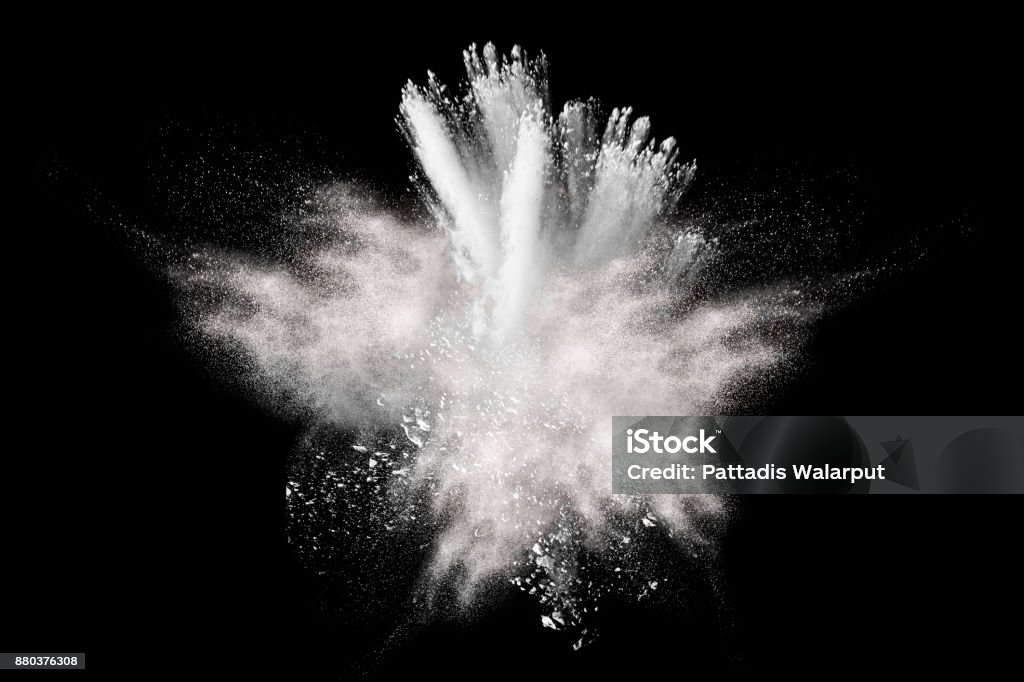 Freeze motion explosion of white dust on  black background. By throwing talcum powder out of hand. Stopping the movement of white powder on dark background. Exploding Stock Photo