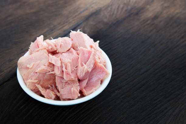 istock bowl of tuna chunks on wood table background. Dark tone 880379896