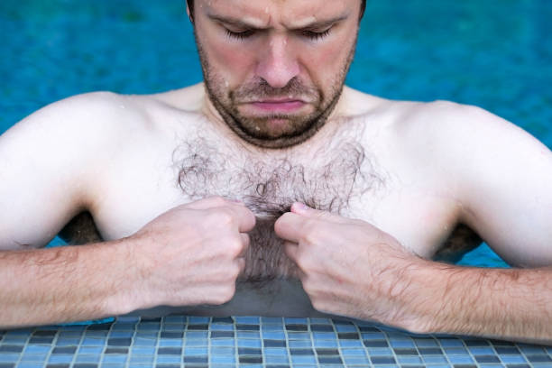 tizio caucasico che nuota in piscina. sta guardando i suoi capelli sul petto - hairy men shaving chest foto e immagini stock