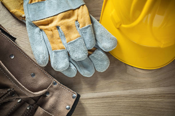 istock Leather tool belt protective gloves hard hat on wooden board 880400466