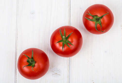 Red tomatoes on white wooden background. Studio Photo