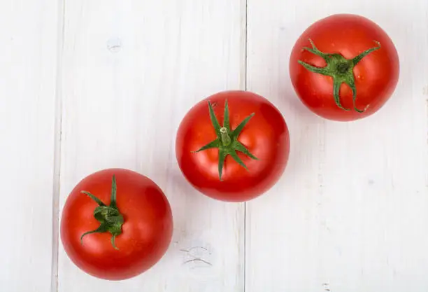 Photo of Red tomatoes on white wooden background