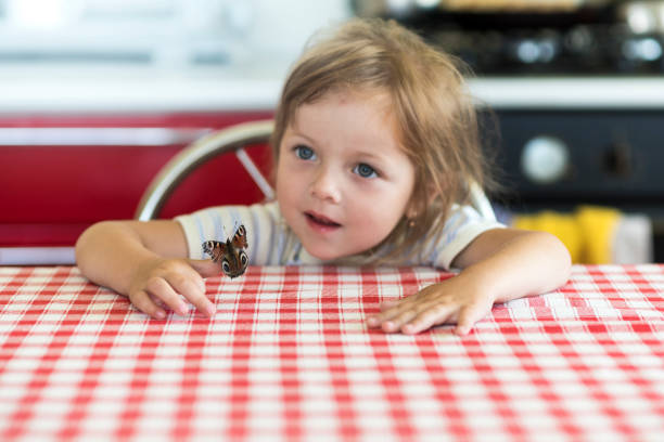 Little girl holds on the hand the Aglais io butterfly and watches for him Little girl holds on the hand the Aglais io butterfly and watches for him, emotions lepidopterans stock pictures, royalty-free photos & images