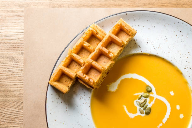 sopa de calabaza y zanahoria con waffles belgas y crema sobre fondo de madera rústica. plana se pone con espacio vacío - pumpkin soup soup cup pumpkin fotografías e imágenes de stock