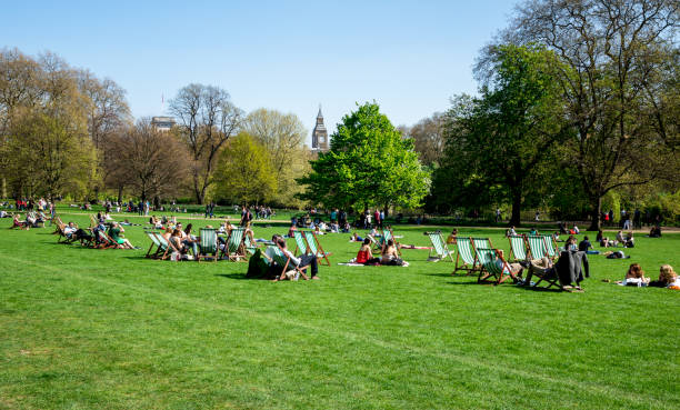 People relax in London St James Park with Big Ben seen in background, England stock photo