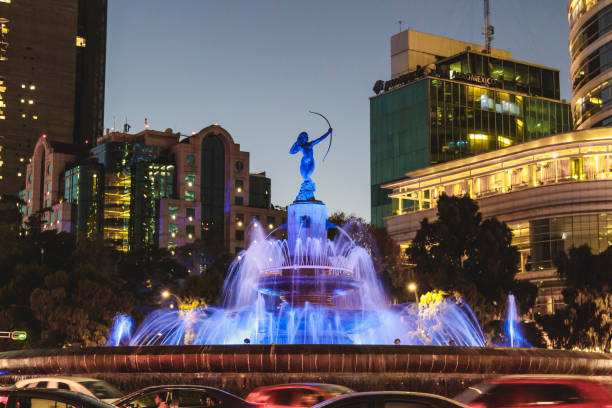 Landmark roundabout along Paseo de la Reforma with skyscrapers in the background, at sunset. The fountain was inaugurated on 1942, it is a collaboration between Architect Vicente Mendiola and Sculpture Juan Olaguibel.