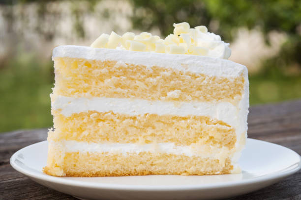 decorar bizcocho de vainilla con crema y chocolate blanco. rodajas de pastel en el plato blanco. sirve en la mesa de madera. - cake fotografías e imágenes de stock