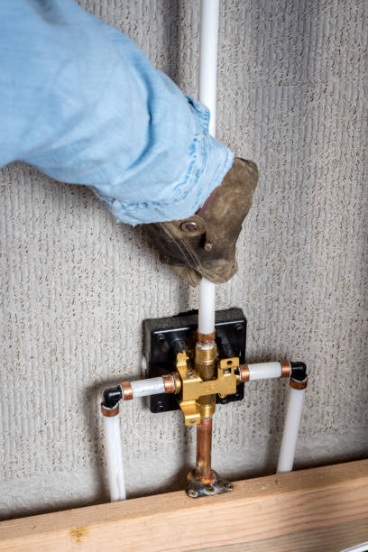 istock Plumber pulls pipe into place on the back of a shower 880446972